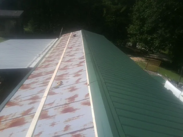Old rusted panels beside newly installed green metal roofing — Wind Damage Roof Repair by Roofing Brothers in Shippensburg