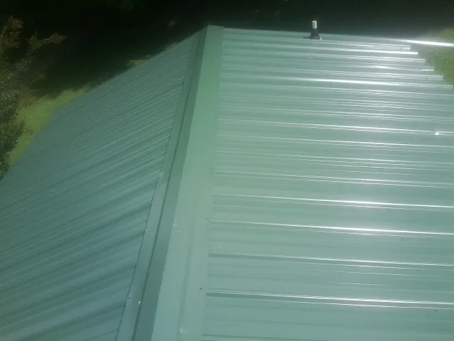 New green metal panels meeting at the ridge of a roof — Flat Roof Repair work by our crew in Shippensburg