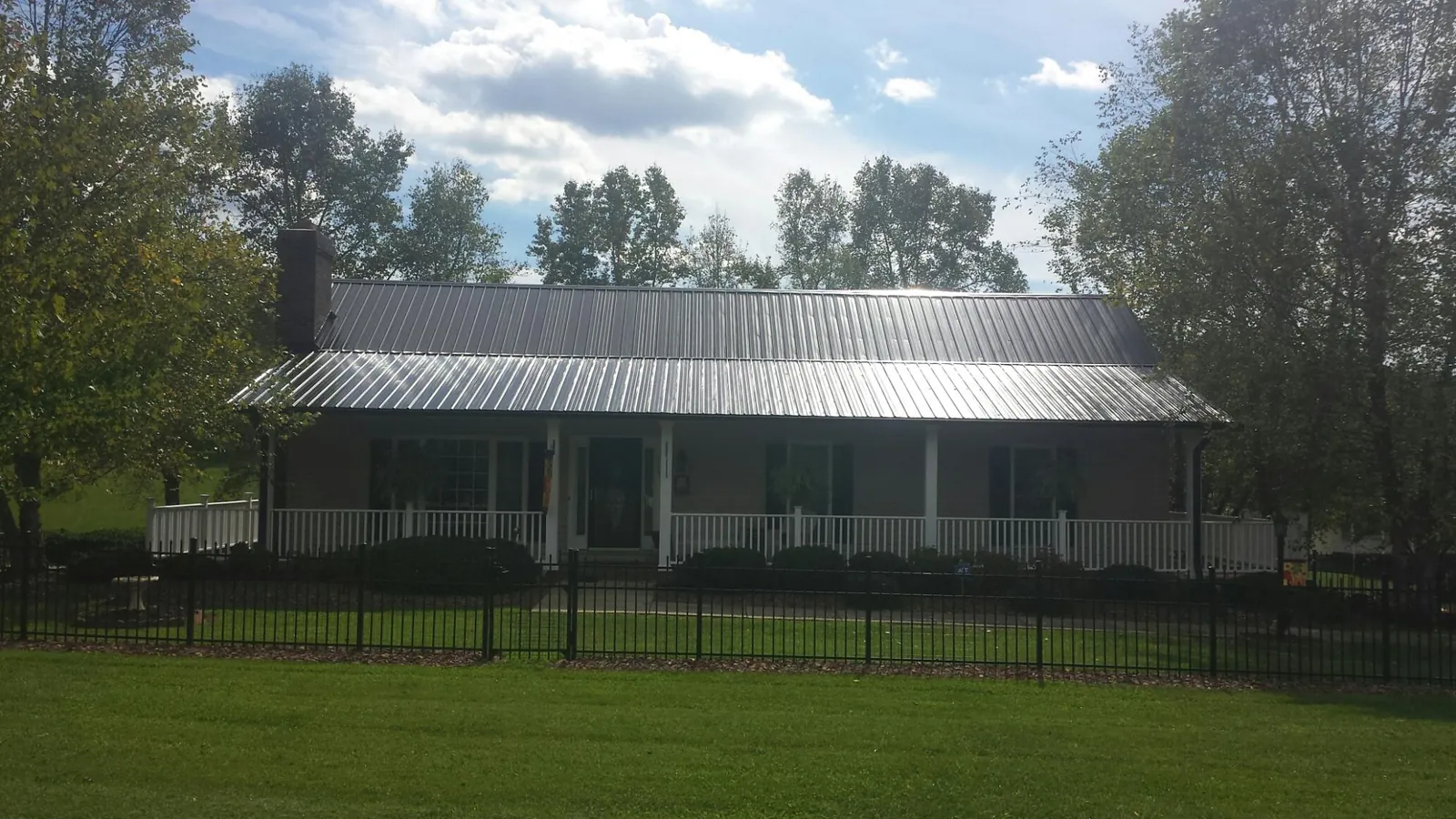 Gray metal roof on a brick ranch with a full width front porch — Gutter Guard Installation work by our crew in Shippensburg