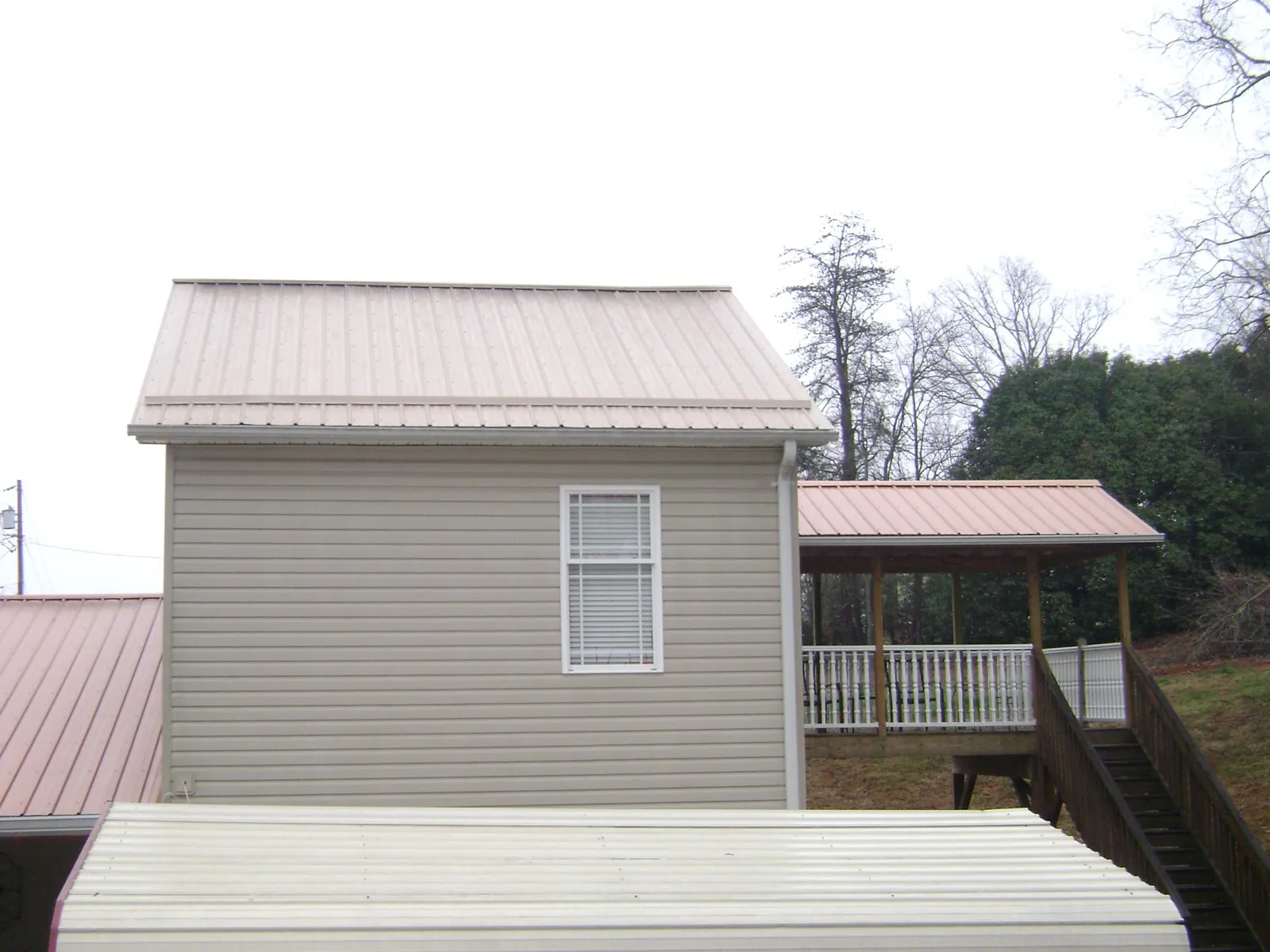 Tan metal roofs on a two story addition and attached porch, from a Roof Replacement job in Shippensburg