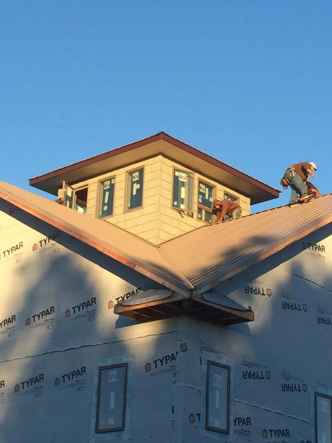 Roofers working around a rooftop cupola on a new metal roof at sunset — Roof Waterproofing in Shippensburg by Roofing Brothers